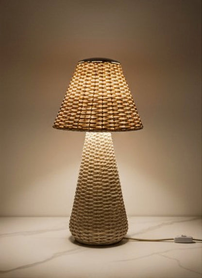 Handwoven Rattan Table Lamp illuminated on marble surface, studio front view