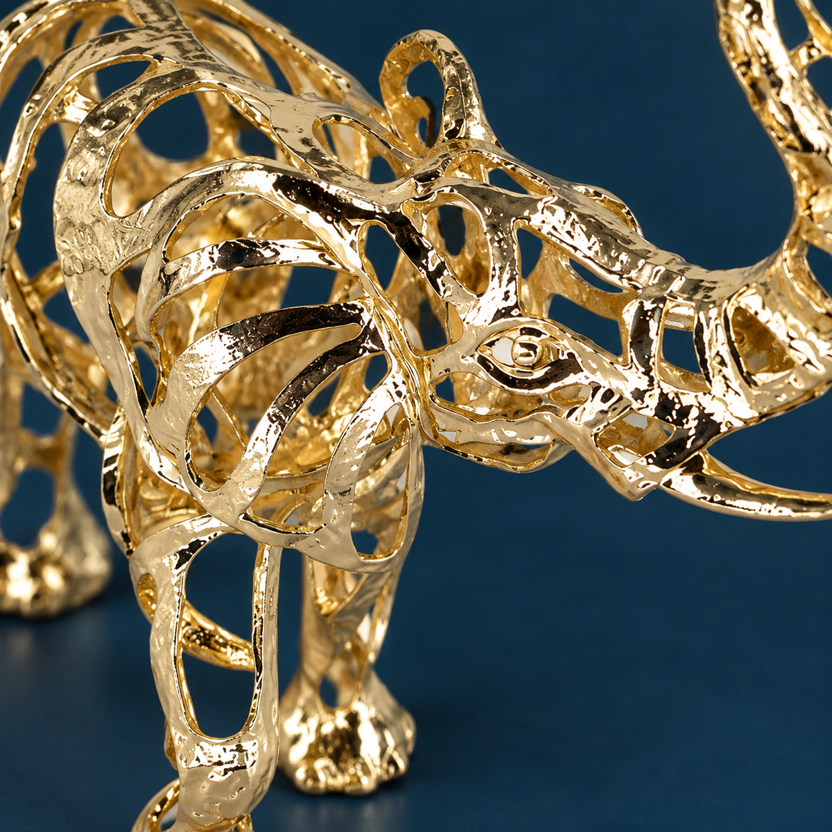Close view of the Warm Gold elephant's openwork ear, head and reflective alloy finish