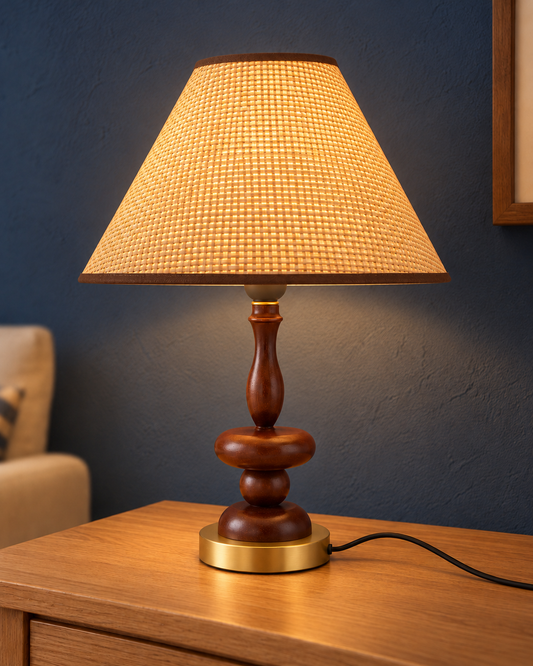 Contour table lamp illuminated through its fine woven shade on an oak console