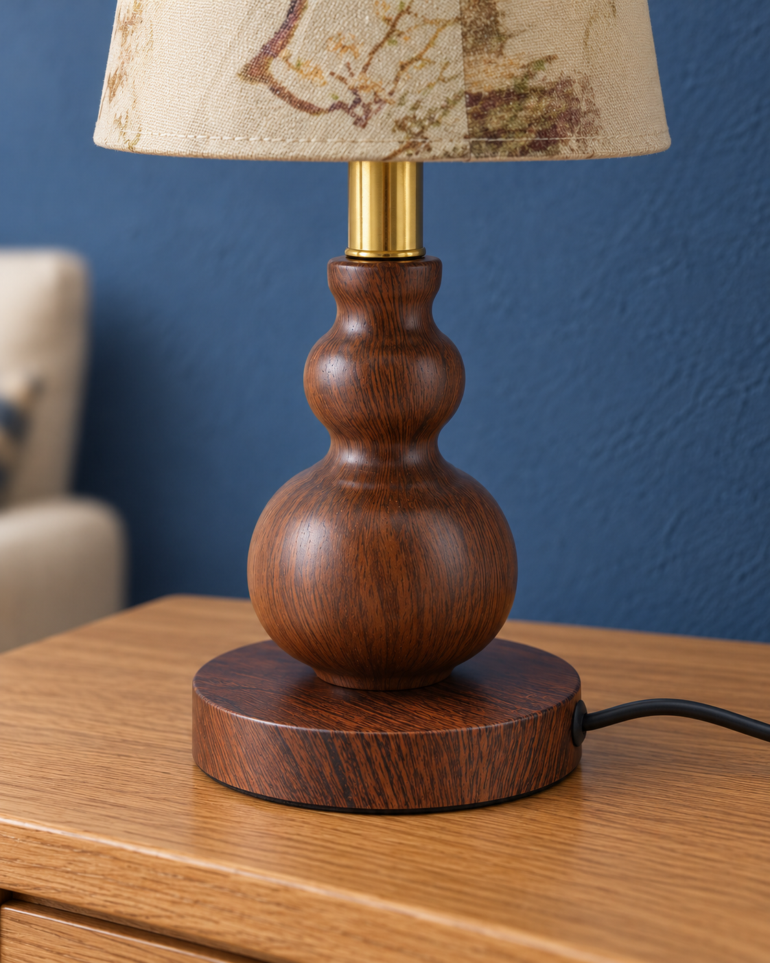 Close-up of the Spindle lamp rounded wood-look metal base and gold-tone stem
