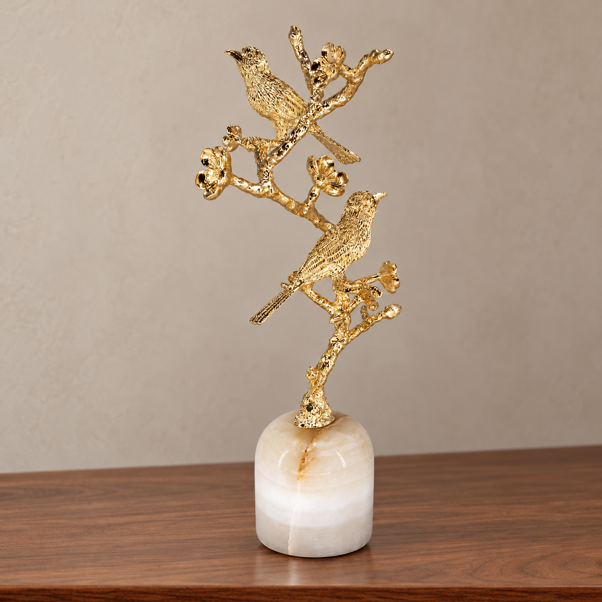 Perch sculpture with two gold-tone birds on a flowering branch and white stone base — front view