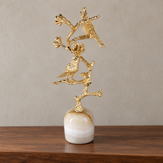 Perch birds on a flowering gold-tone branch — reverse view showing white stone base